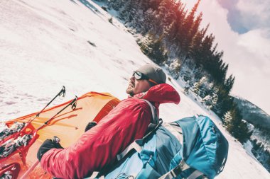 Adamın yanında kış çadırda. Turistik aşırı koşullarda. Kar ayakkabıları, trekking Polonyalılar ve sırt çantası. Kış dağda kamp. Kar turuncu çadırda.