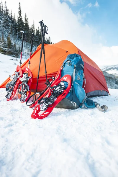 スノーシュー バックパック トレッキング スティック テントの近きます 冬用は 森林および山の背景にハイキングします 山でキャンプ 冬の登頂 — ストック写真