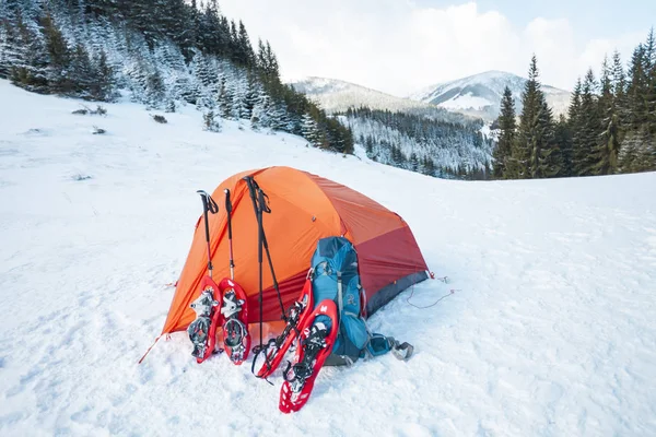 スノーシュー バックパック トレッキング スティック テントの近きます 冬用は 森林および山の背景にハイキングします 山でキャンプ 冬の登頂 — ストック写真