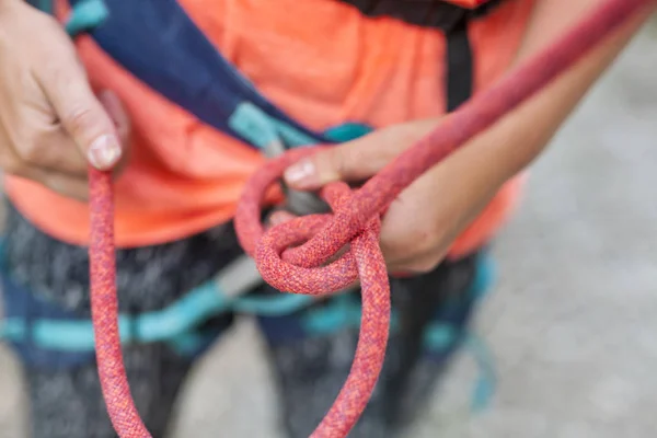 The girl is learning to knit knots. A climber knits a knot. A woman prepares to climb a climbing route. Insurance and safety in rock climbing. Safety rope. Node eight.
