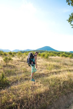 Bir oğlan bir sırt çantası içinde oturuyor. Çocuk ailesiyle birlikte dolaşıyor. Bir çocukla tırmanma. Anne Bebek taşır. Küçük bir seyahat. Bir kadın bebeğini taşıyor. Çocuklarla seyahat.