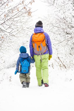 Çocuk annesiyle bir orman karla kaplı yolda yürür. Kış tatili. Bir sırt çantası olan bir çocuğun annesi ile eğleniyor.