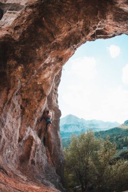 Bir kadın rock tırmanıyor. Rock bir kemer şeklinde. Mağara. Ekstrem Sporlar. Doğal bir rahatlama atlet trenlerde. Atlet zor bir tırmanış rota üstesinden gelir. Türkiye'de dağcılık.