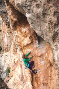 Bir kaya tırmanışçısı. Kız bir tırmanış yapıyor. Doğada spor. Açık havada aktif yaşam tarzı ve spor. Aşırı bir hobi. Cesur kadın..