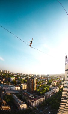İki bina arasında uzanan bir çizgi boyunca bir adam girer. Bir adam denge irtifada yakalar. Highline şehri.