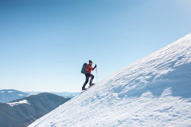Bir adam dağın zirvesine tırmanıyor. Dağcı kar ayakkabıları bir sırt çantası taşımak. Yolculuk kışın dağlarda. Doğada aşırı tatil. Aşırı koşullarda Turizm.