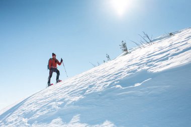 Bir adam dağın zirvesine tırmanıyor. Dağcı kar ayakkabıları bir sırt çantası taşımak. Yolculuk kışın dağlarda. Doğada aşırı tatil. Aşırı koşullarda Turizm.