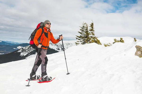 一个人爬上山顶 登山运动员在雪地鞋背着一个背包 在冬天的山上旅行 大自然中的极端假期 极端条件下的旅游者 — 图库照片