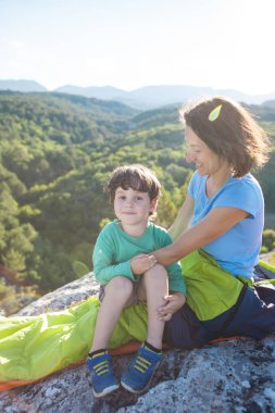 Dağın tepesinde kamp yapmak. Anne ve çocuk birlikte seyahat ediyorlar. Bir kadın ve oğlu tırmanıştan sonra dinleniyor. Uyku tulumundaki kız. Annelik kucaklaması..