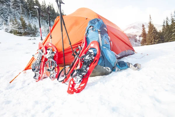 スノーシュー バックパック トレッキング スティック テントの近きます 冬用は 森林および山の背景にハイキングします 山でキャンプ 冬の登頂 — ストック写真