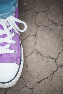 Kırık yeryüzünde bir menekşe spor ayakkabı. Şık ayakkabılar kapatın. Moda ayakkabı kadın ayakları.