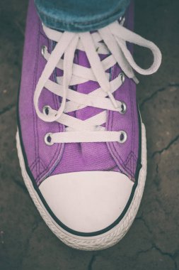 Kırık yeryüzünde bir menekşe spor ayakkabı. Şık ayakkabılar kapatın. Moda ayakkabı kadın ayakları.