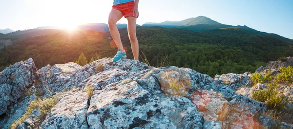 A girl is running in the mountains. A woman goes in for sports in nature. Slender brunette on top of a mountain at sunset.