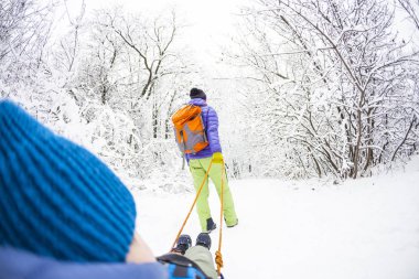 Bir kadın bir çocuk bir kızak üzerinde taşıyor. Anne oğlu ile kar izinde yürür. Neşeli kış tatili. Kış eğlence. Bebek kızak üzerinde.