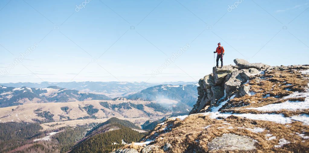 Climber with a backpack on top on a Sunny day. A man went up on the mountain, people traveling through the beautiful wilderness, man climbed to the top of a mountain and enjoying his success.