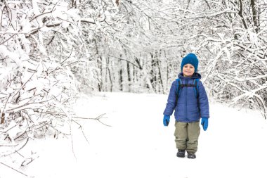 Bir çocuk kar üzerinden çalışır. Bir çocuk bir sırt çantası ile kışın parkta yürüyor. Kış tatili. Çocuk karda sevinir.