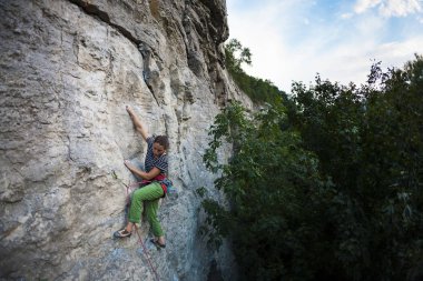 Bir kadın zor bir tırmanış rota üstesinden gelir. Spor kız kayaya tırmanıyor. Güç ve dayanıklılık eğitim. Atlet üzerinde doğal bir rahatlama tırmanıyor.