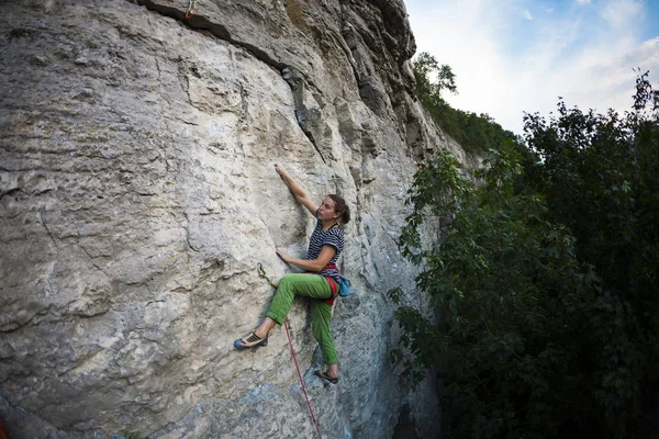 一个强壮的女孩爬上岩石 攀岩训练 登山者爬上岩石 运动的性质 极端的爱好 克服对高度的恐惧 力量和耐力训练 — 图库照片