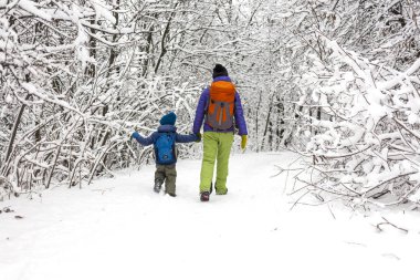 Çocuk annesiyle bir kar kaplı orman yolu üzerinde yürür. Kış tatili. Bir sırt çantası olan bir çocuğun annesi ile eğleniyor.