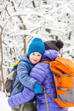 Çocuk anne sarılmak. Bir çocuk ve onun anne kış ormanda yürüyor. Bir çocuk annesini öper. Kadın oğlunu destekler. Annelik.