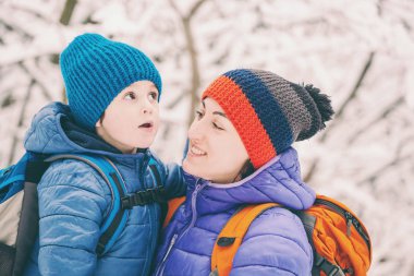 Çocuk anne sarılmak. Bir çocuk ve onun anne kış ormanda yürüyor. Bir çocuk annesini öper. Kadın oğlunu destekler. Annelik.
