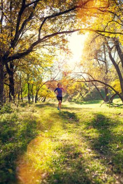 Kız sonbahar Parkı ile çalışır. Doğada ince kadın trenler. Ormanda spor. Esmer bir toprak yol boyunca çalışır. Runner trenler engebeli arazide.