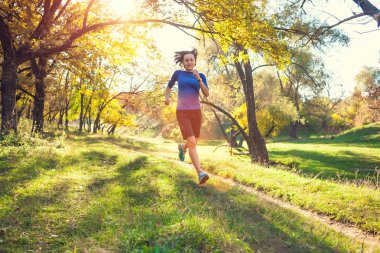 Runner uçuş aşamasındadır. Kız sonbahar Parkı ile çalışır. Doğada ince kadın trenler. Ormanda spor. Esmer bir toprak yol boyunca çalışır.