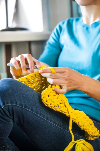 뜨개질 여자는 소파에 앉아서 뜨개질 원사에서 두꺼운 스레드 뜨개질 — 스톡 사진
