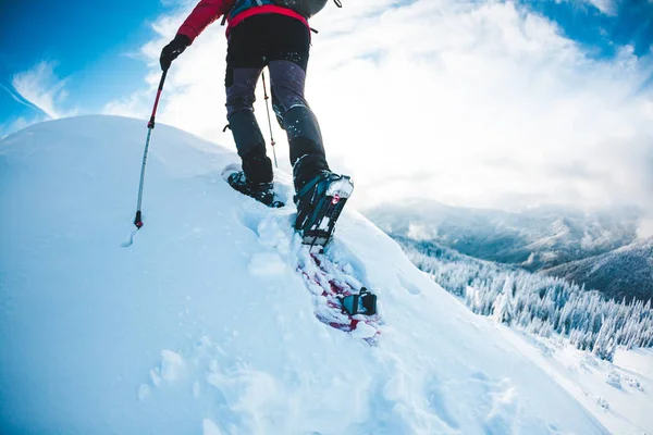 冬の山でスノーシューの人 トレッキング スティックと登山者は雪の中を歩きます 冬の登頂 美しい空の雲 — ストック写真