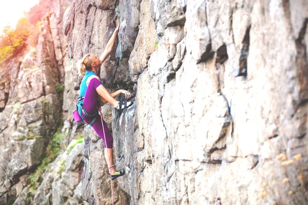 A woman climbs the rock. Training on natural terrain. Extreme sport. The climber trains on a natural relief.