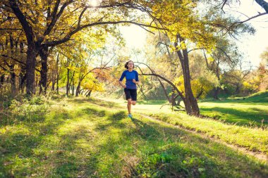 Kız sonbahar Parkı ile çalışır. Doğada ince kadın trenler. Ormanda spor. Esmer bir toprak yol boyunca çalışır.