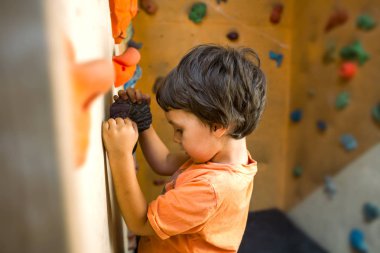 Tırmanma duvarı dağcı trenlerde. Çocuk üzerinde yapay bir rahatlama tırmanmaya eğitimli. Çocuk spor için gidiyor. Aktif yaşam tarzı.