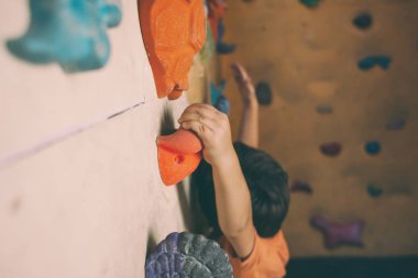 Tırmanma duvarı dağcı trenlerde. Çocuk üzerinde yapay bir rahatlama tırmanmaya eğitimli. Çocuk spor için gidiyor. Aktif yaşam tarzı.