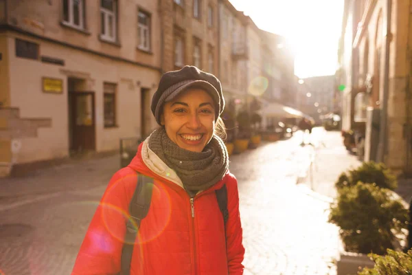 Smiling girl on the city street. Young woman walking through the old town. The girl in the cap travels around European cities.