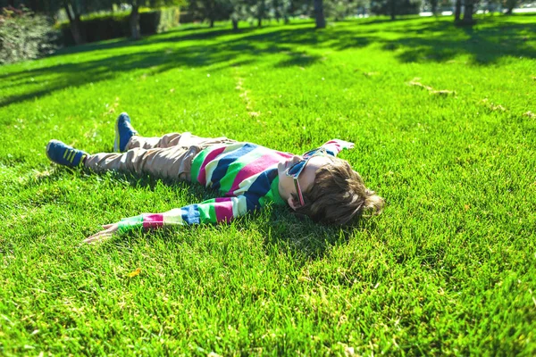 那男孩躺在草地上 孩子在绿色的草坪顶视图上休息 孩子在草坪上玩的开心 — 图库照片