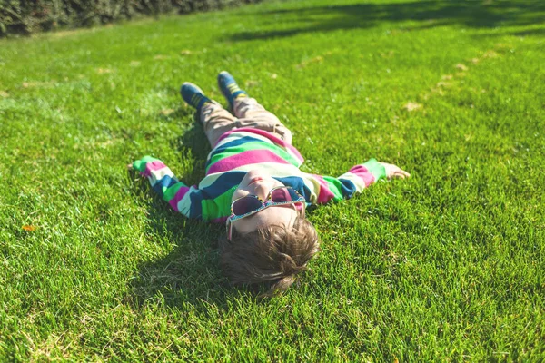 那男孩躺在草地上 孩子在绿色的草坪顶视图上休息 孩子在草坪上玩的开心 — 图库照片