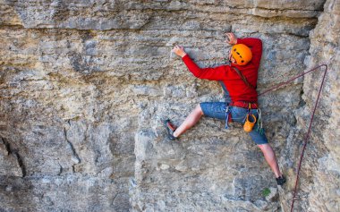 Miğferli bir tırmanıcı dağın tepesine tırmanır. Doğadaki spor aktiviteleri.
