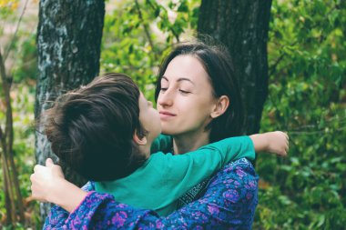Annemin kucaklama. Çocuk annesi sarılıyor. Doğada oğluyla gülümseyen kadın yürüyor. Bir çocuk olan bir kadın portresi. Aile ile harcanan zamanın yüzdesi.