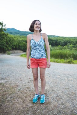 Bir ince kız doğada dinleniyor. Atlet bir çalıştırdıktan sonra istirahat ediyor. Kadın bir dağ gölü arka planda.