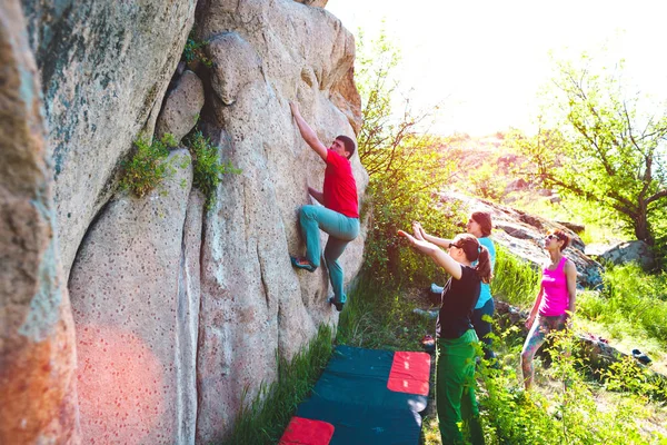 一个攀岩者爬上一块石头 他的搭档保险 运动员在户外抱石赛 一群在新鲜空气中参与体育运动的朋友 男人和女人在大自然中休息 — 图库照片
