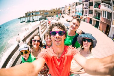 Arkadaşlar denizde sakin ol. İki aile çocukları ile seyahat. Selfies okyanus kıyısında. Kadın ve erkek tatil beldesi iskele yürümek.