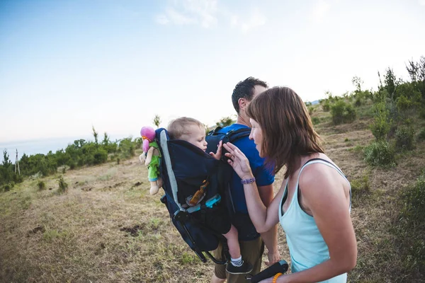 子供との家族旅行 バックパックに彼の息子を運ぶ 家族で歩きます 少年は山の中の彼の両親と旅行です 女性は彼女の息子と遊んでください — ストック写真