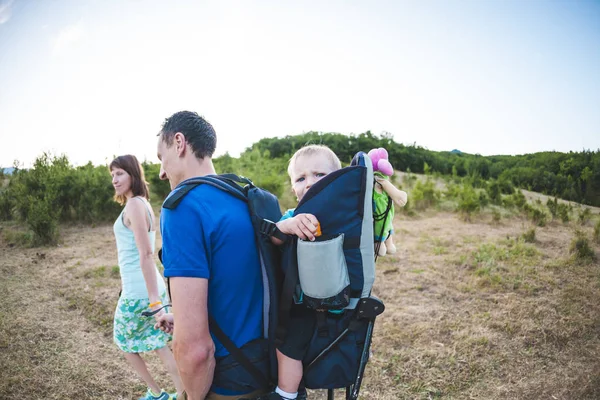 子供との家族旅行 バックパックに彼の息子を運ぶ 家族で歩きます 少年が山で彼の両親と一緒に旅行します — ストック写真