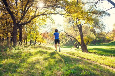 Kız sonbahar Parkı ile çalışır. Doğada ince kadın trenler. Ormanda spor. Esmer bir toprak yol boyunca çalışır.