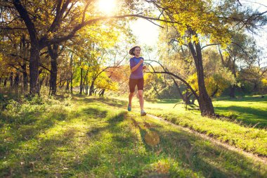 Runner uçuş aşamasındadır. Kız sonbahar Parkı ile çalışır. Doğada ince kadın trenler. Ormanda spor. Esmer bir toprak yol boyunca çalışır.