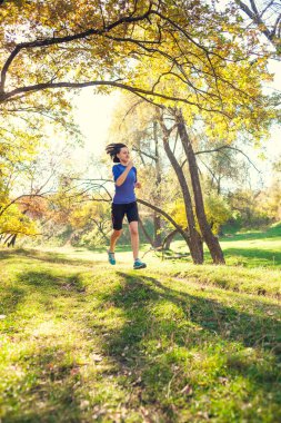 Runner uçuş aşamasındadır. Kız sonbahar Parkı ile çalışır. Doğada ince kadın trenler. Ormanda spor. Esmer bir toprak yol boyunca çalışır.