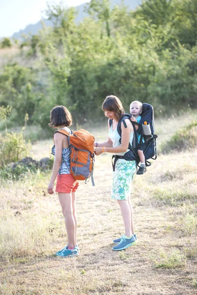 Duas Mulheres Viajam Com Uma Criança Uma Mulher Ajusta Mochila — Fotografia de Stock