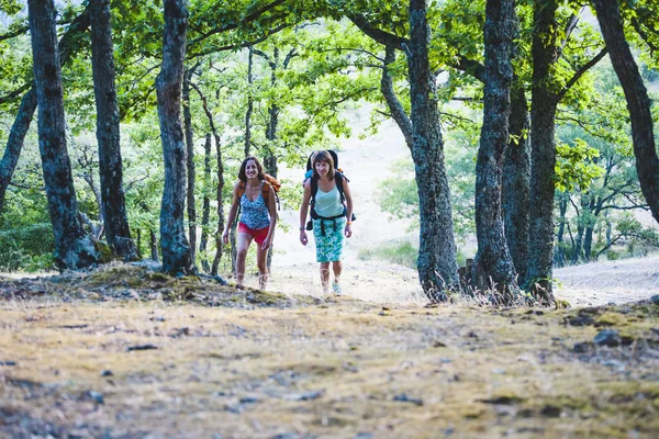 人の女性は 子供と一緒に旅行されます 女の子は バックパックに彼女の息子を運ぶ ガール フレンドは一緒に旅行します 赤ちゃんと一緒に山を登る — ストック写真