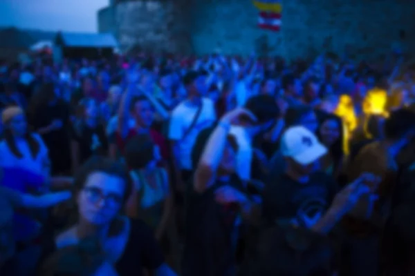 A crowd of people at the music festival. People having fun at the concert. The blur effect.