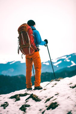Bir adam sırt çantası ve trekking kış dağlar fonunda yapışır. Dağcı üstünde belgili tanımlık tepe. Dağlarda kış tırmanışı.